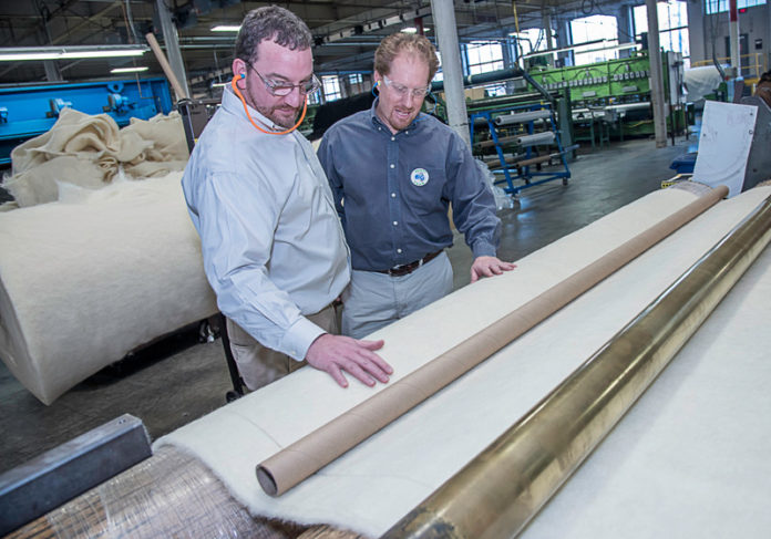 IN GOOD COMPANY: Max Brickle, right, president of the holding company the Brickle Group, examines wool material used in mattress covers with Director of Operations Andrew Dudka. The companies within the Brickle Group produce everything from wool blankets for the U.S. Department of Defense to the yarn used in MLB baseballs and the wool fabric used in Homeland Security uniforms at airport-security checkpoints. / PBN PHOTO/MICHAEL SALERNO