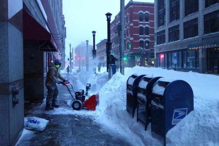 DIGGING OUT: A man uses a  snowblower to help clear the sidewalk  on Dorrance St. in Providence during  last week’s blizzard. / PBN PHOTO/FRANK MULLIN