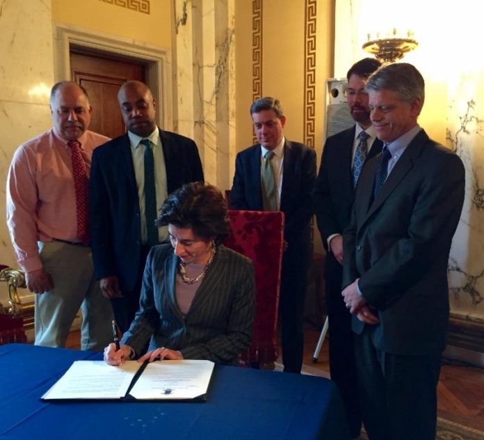 GOV. GINA M. RAIMONDO on Tuesday signed an executive order to make Rhode Island a more attractive place for businesses to operate. From left to right behind Raimondo, Terry Gray from the Department of Environmental Management; Sidney McCleary, director of business regulation; Jonathan Womer, director of the Office of Budget and Management; Erik Godwin, director of the Office of Regulatory Reform; and Scott Jensen, director of the Department of Labor and Training. / COURTESY GOVERNOR'S OFFICE