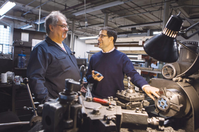 LONG-TIME TRENDSETTER: Wardwell Braiding has been setting the standard for braiding machines throughout its 116-year history at its Central Falls facility, where company Vice President John Tomaz, right, talks with first-class machinist Bob Blanchette. / PBN PHOTO/RUPERT WHITELEY