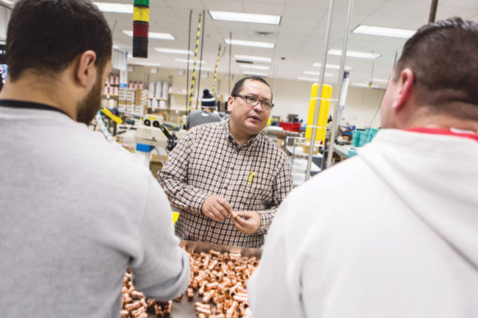 LOCKING IN PROGRESS: Quick Fitting Vice President of Engineering Libardo Ochoa, center, knows that innovation comes from all members of the organization, including workers on the floor. / PBN PHOTO/RUPERT WHITELEY