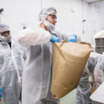 IN THE MIX: Edesia Production Lead Victor Fernandez, foreground, empties a bag with raw ingredients for a new batch of food. / PBN PHOTO/RUPERT WHITELEY