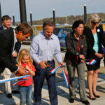 FROM LEFT, Volvo Ocean Race CEO Knut Frostad, his daughter Pernilla, Congressman David N. Cicilline, Gov. Gina M. Raimondo, R.I. DEM Director Janet Coit, and state Senate President M. Teresa Paiva Weed cut the ribbon to the new North Pier at Fort Adams during the opening ceremony for the Volvo Ocean Race Newport Race Village last week. In the background is Sail Newport Executive Director Brad Read. / COURTESY DAN NERNEY/SAIL NEWPORT/VOLVO OCEAN RACE NEWPORT