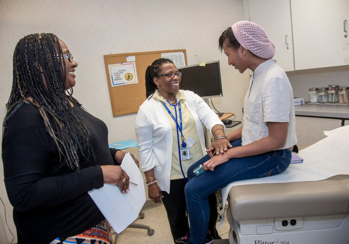 LOCAL TREATMENT: Vanessa Semedo, right, a senior at Central Falls High School, at the school's health clinic with Sara Perry, left, Central Falls practice manager for Blackstone Valley Community Health Care, and LeTotha Wiggins, medical assistant. / PBN PHOTO/MICHAEL SALERNO