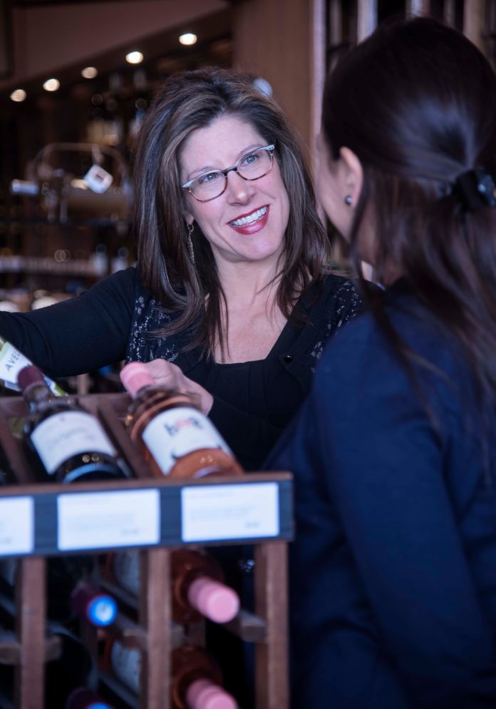 FINE WINE: Jessica Granatiero, owner of The Savory Grape in East Greenwich, left a career in public relations to create the wine shop in 2006. Above, she speaks with store manager Tulay Lawton. / PBN PHOTO/MICHAEL SALERNO