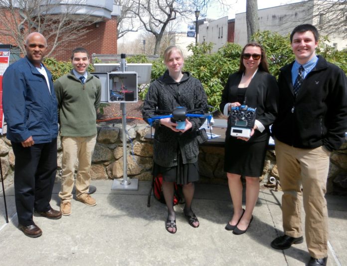 FOUR URI engineering students won first place in the University Design Competition for Addressing Airport Needs, sponsored by the Federal Aviation Administration, for inventing a drone detection system. From left to right, Alan Andrade, vice president of the Rhode Island Airport Corporation, and students Stephen Pratt, Catherine LiVolsi, Krista Brouwer and Thomas Cottam. LiVolsi is holding a drone, and Brouwer is holding the drone detection system that they invented.