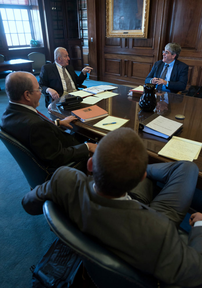 COMMON GROUND: Retired state Supreme Court Chief Justice Frank J. Williams, center, speaks with attorneys Anthony DeSisto, right, Michael A. Kelly, left, and Jackson Parmenter, right foreground, at a mediation session. / PBN PHOTO/ MICHAEL SALERNO