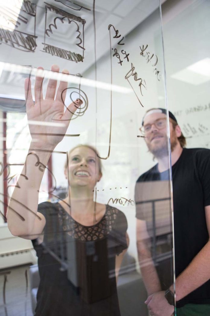 INTENSE FOCUS: Team members are assigned only one project at a time so they can deliver the best results for a client. Above, Courtney Fanning and Andrew Shedd, member-services supervisors, use a clear board to examine an issue. / PBN PHOTO/RUPERT WHITELEY