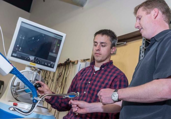 A NEW SURGICAL PATH: Raynham-based Medrobotics' flexible robotic surgical device, being demonstrated by mechanical engineer Ian Darisse, left, and biomedical engineer Rich Kuenzler, allows surgeons better access to body parts. / PBN PHOTO/MICHAEL SALERNO