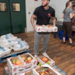 FRESH IDEAS: Alex Mendonca loads heirloom tomatoes at Farm Fresh Rhode Island. / PBN PHOTO/MICHAEL SALERNO