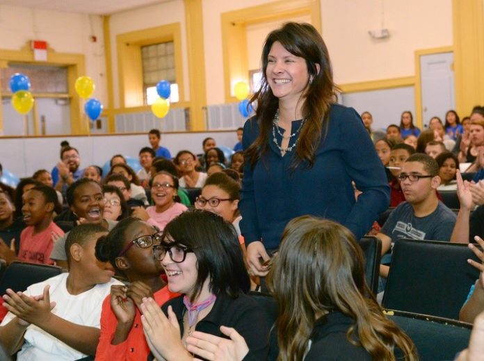 KENDRA BORDEN, making her way to the stage at Samuel Slater Junior High School in Pawtucket Wednesday morning, was awarded $25,000 by the Milken Family Foundation for being named Rhode Island's 2015 Milken Educator Award winner. / COURTESY MILKEN FAMILY FOUNDATION