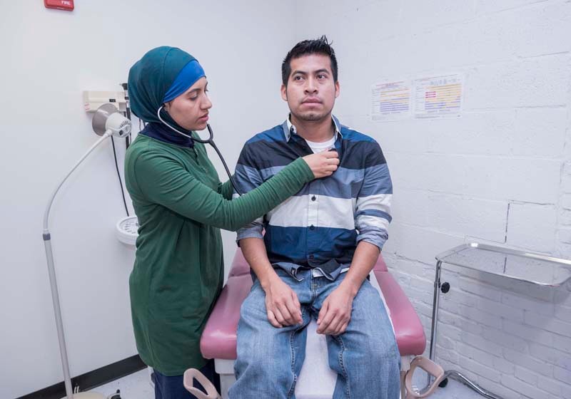 A VALUED SERVICE: The Clinica Esperanza/Hope Clinic in Providence provides free health care to the city's underserved population. Here, Dr. Zineb Benstitou examines Julio Martinez. / PBN PHOTO/MICHAEL SALERNO