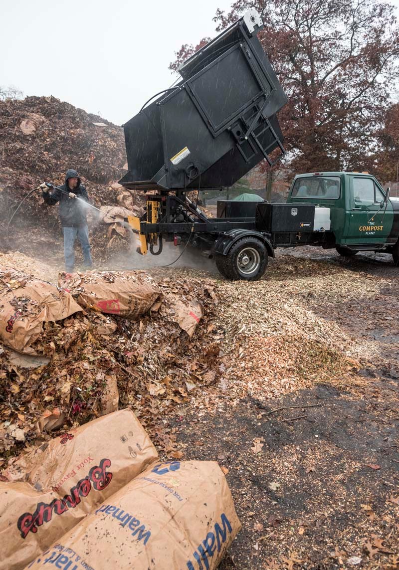 CLEAN AND GREEN: Nat Harris washes The Compost Plant's truck after food scraps were dumped on a compost pile at Earth Care Farm in Charlestown. / PBN PHOTO/MICHAEL SALERNO