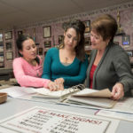 FAMILY ACT: Carmel Therien, right, president of B & M Printing of Cumberland, and her daughters Carissa Therien, left, a clerical and sales representative who handles pre-press and post-press operation, and Kayla (Therien) Marsh, who is in charge of graphic design and office management, view samples. / PBN PHOTO/MICHAEL SALERNO