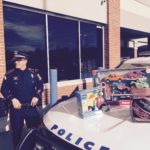 Detective Mark Brasil of the University of Rhode Island Police Department stands on Dec. 12 next to a police cruiser stuffed with toys that will be donated to local families and sick children at Hasbro Children's Hospital. The department held a two-day Stuff-A-Cruiser Holiday Toy Drive outside Walmart in North Kingstown, where shoppers donated more than 3,000 toys, enough to fill nine cruisers. / COURTESY URI POLICE MAJ. MICHAEL JAGODA