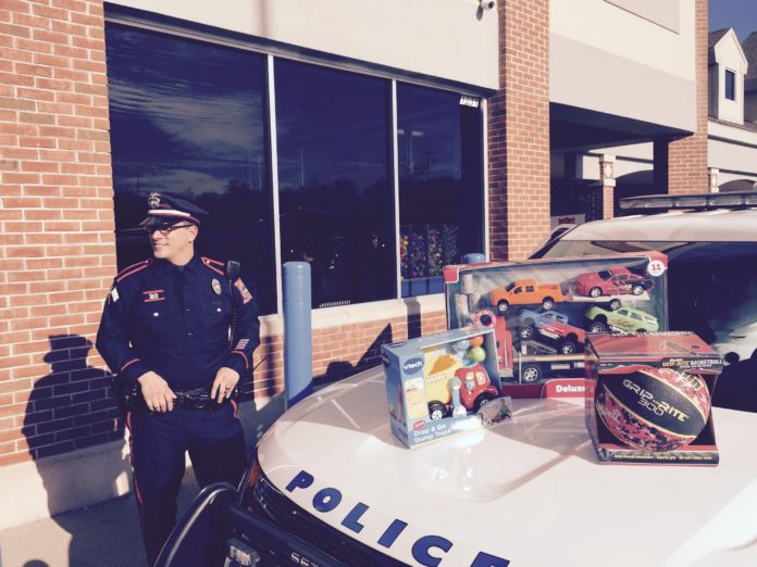 Detective Mark Brasil of the University of Rhode Island Police Department stands on Dec. 12 next to a police cruiser stuffed with toys that will be donated to local families and sick children at Hasbro Children's Hospital. The department held a two-day Stuff-A-Cruiser Holiday Toy Drive outside Walmart in North Kingstown, where shoppers donated more than 3,000 toys, enough to fill nine cruisers. / COURTESY URI POLICE MAJ. MICHAEL JAGODA