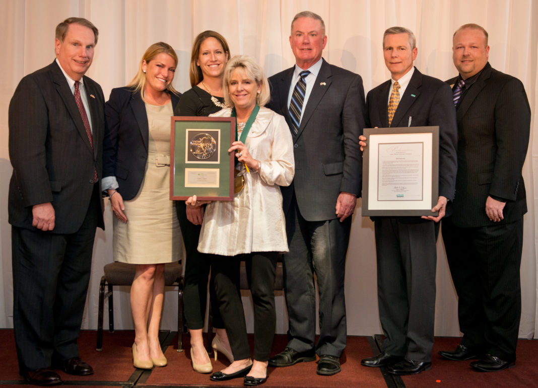 Jane Schwab, along with her daughters Taylor Schwab and Lindsay Haun, accept a 2015 posthumous award for long-time JA board member William Schwab of Amica Insurance. With the Schwab family are Steve Kitchin of JA, Representative Joseph McNamara, Amica President Robert DiMuccio, and JA President Lee Lewis.