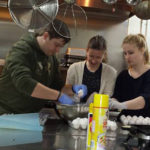 RWU students spend spring break in community service programs for nonprofits From left, Sean Carroll, Caroline Keane and Katie Carpenter, students from Roger Williams University, help prepare meals for local residents at the Mathewson Street Church in Providence as part of the university’s “Stay Break” program. In the immersive, weeklong service learning experience students stay on campus during spring break while they serve nonprofits in nearby communities. / COURTESY ROGER WILLIAMS UNIVERSITY