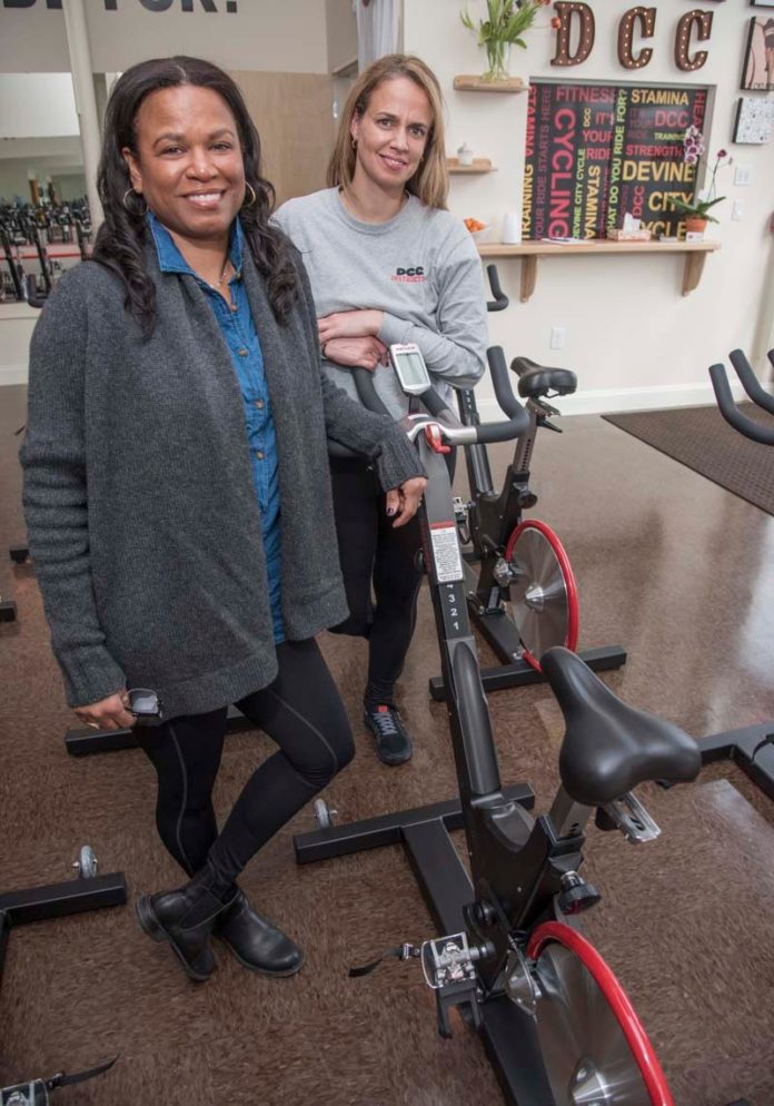 A FAMILY SPIN: Sisters Mona Devine Kronholm, left, and Alexis Devine are co-owners of the Providence cycling and fitness studio Devine City Cycle. / PBN PHOTO/MICHAEL SALERNO