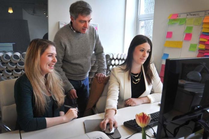 SELLING SUCCESS: Soren Ryherd, center, founder of The Retail Project RI LLC, an initiative launched through the Innovation Fellowship program at the Rhode Island Foundation, looks over products with Lindsay Stickel, brand development manager, left, and Paige Snyder, project manager, at their Wayland Square office in March. / PBN PHOTO/FRANK MULLIN