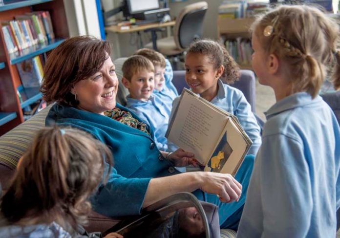 WHY IT MATTERS: Amanda McMullen, chief operating officer at Meeting Street in Providence, reads to some of the 5-year-old students in the school's library. From left, Sophia Cairone, Braydon Stelmach, Atticus Michael, Karyss Williams, and Georgia Marton. / PBN PHOTO/MICHAEL SALERNO WHY IT MATTERS: Amanda McMullen, chief operating officer at Meeting Street in Providence, reads to some of the 5-year-old students in the school's library. From left, Sophia Cairone, Braydon Stelmach, Atticus Michael, Karyss Williams, and Georgia Marton. / PBN PHOTO/MICHAEL SALERNO