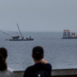 PEOPLE LOOK out at a Deepwater Wind LLC offshore wind farm under construction off the coast of Block Island in July 2015. / BLOOMBERG NEWS FILE/SHIHO FUKADA