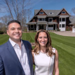 FORM AND FUNCTION: Jennifer and Gary Mello, owners of Seekonk-based The Mello Group, are seen in front of a home that Gary Mello designed. The 4,000-square-foot home has a large, open living area, a 12-foot island in the kitchen and a two-sided, two-story chimney with a fireplace both inside and out. / PBN PHOTO/MICHAEL SALERNO
