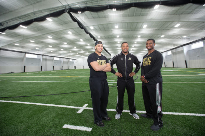 THREE MEMBERS OF BRYANT UNIVERSITY'S football team, from left, Josh Jefferson, Aaron Gilmer and Brandon Owens, pose in the new Conaty Indoor Athletic Center at the school's Smithfield campus. / COURTESY BRYANT UNIVERISTY