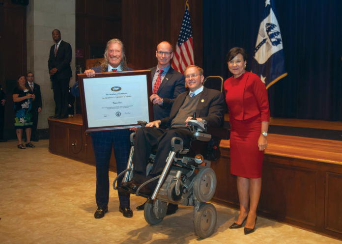 JOHN HAZEN White Jr., chairman and CEO of Taco Comfort Solutions, on left, holds the U.S. Department of Commerce “E” award at Monday’s awards ceremony in Washington, D.C. With him, left to right, are Wil VandeWiel, Taco chief operating officer; U.S. Rep. James R. Langevin and U.S. Secretary of Commerce Penny Pritzker. / COURTESY TACO COMFORT SOLUTONS