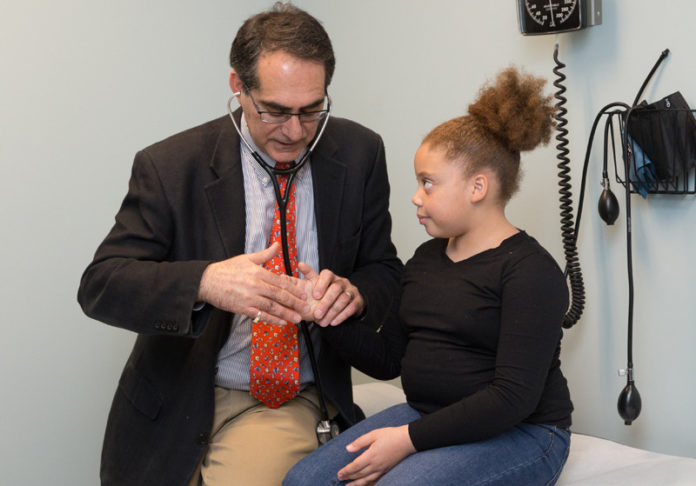 HANDS-ON CARE: Dr. Nathan Beraha, medical director at Anchor Medical Associates, examines 9-year-old Cailyah Correia at Anchor Medical in Lincoln. / COURTESY LIFESPAN