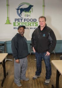 PLANNING PAYS OFF: Employee Dwayne Gibson, left, is seen with regional director of operations Jeffrey Lavalley at Pet Food Experts Inc. in Cumberland. Gibson landed the job before he was scheduled to be released from prison. / PBN PHOTO/TRACY JENKINS
