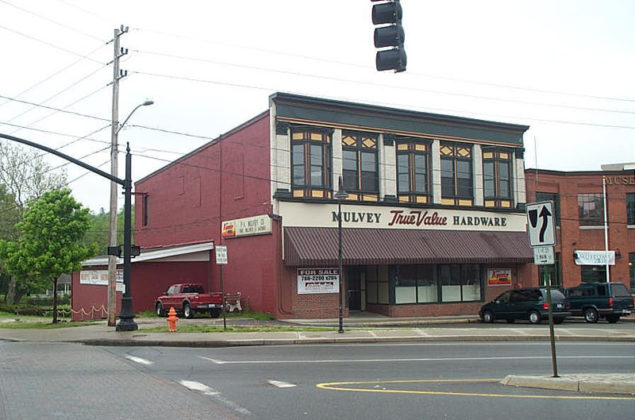 BEFORE AND AFTER: The hardware store had an exterior of red-painted brick and was vacant for many years. The multiple layers of paint could not be removed, so the architect switched gears and repainted the building in a neutral color. The entrance was moved to the left, and windows were replaced. Another entrance providing access to the apartments is at right.