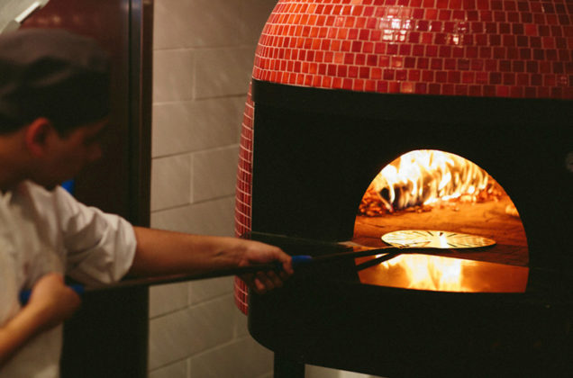 THE REAL THING: Avvio in Garden City in Cranston features an open kitchen with a handcrafted, wood-burning oven imported from Italy. The oven enables line cook Dylan Nieves, above, to create authentic Neapolitan-style pizza and dishes. / COURTESY NEWPORT RESTAURANT GROUP