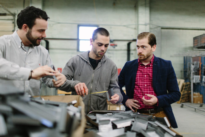 A SIGN OF THE TIMES: Custom Design's point-of-sale display manufacturing business has seen double-digit yearly growth since 2013, while committing to build everything in the U.S. From left, account manager Taylor Kenney, production manager Jesse Godin and Vice President Adam Dias are seen at the North Kingstown company. / PBN FILE PHOTO/RUPERT WHITELEY