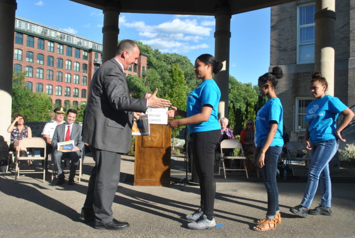 Pawtucket Mayor Donald Grebien accepts a copy of the Building Healthy Neighborhoods Action Plan from Pawtucket Boys & Girls Club Keystone Club Members Anna Gomes, Arizella Baptista and Serenity Perry.. / COURTESY LISC RHODE ISLAND