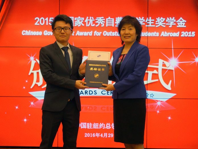 Yufei Tang, a doctoral student in electrical engineering at the University of Rhode Island, receives the Chinese Government Award for Outstanding Students Abroad from China’s Consul General Qiyue Zhang. / COURTESY YANG ZHANG