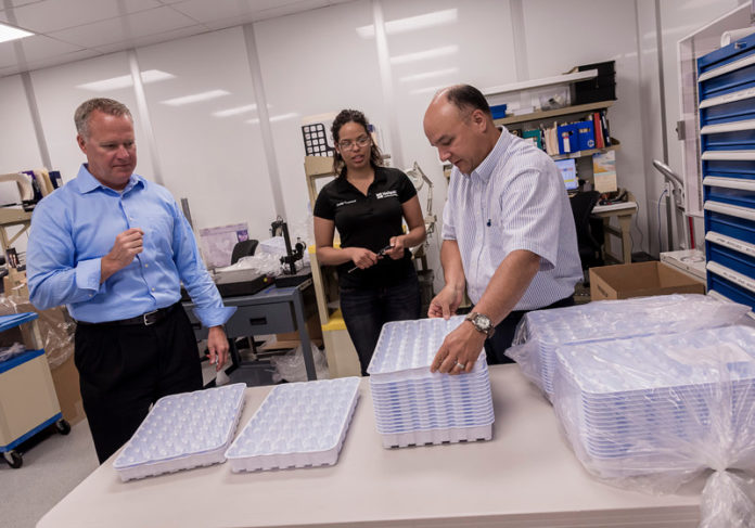 FROM LEFT TO RIGHT, MICHAEL P. Kelly, president and CEO of Nelipak, Santa Valenzuela, quality technician and Michael Spolidoro, general manager, examine some of the custom-designed thermoform trays that the company produces for housing medical devices. / PBN FILE PHOTO/MICHAEL SALERNO