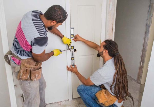 FOOT IN THE DOOR: From left, Samuel Andrade, site supervisor, and Helder Ferreira, superintendent of construction for Pawtucket Central Falls Development, work on a door in a residence on Garfield Street in Central Falls. Ferreira was first hired by the nonprofit for a summer position in 1998. / PBN PHOTO/TRACY JENKINS