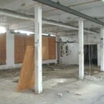 PAST TIME: In this "before" image, the original support posts, constructed of heavy timber, are visible at center, along with what remained of the factory use. The windows were boarded, at left.