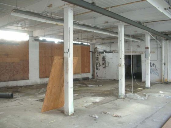 PAST TIME: In this &quot;before&quot; image, the original support posts, constructed of heavy timber, are visible at center, along with what remained of the factory use. The windows were boarded, at left.