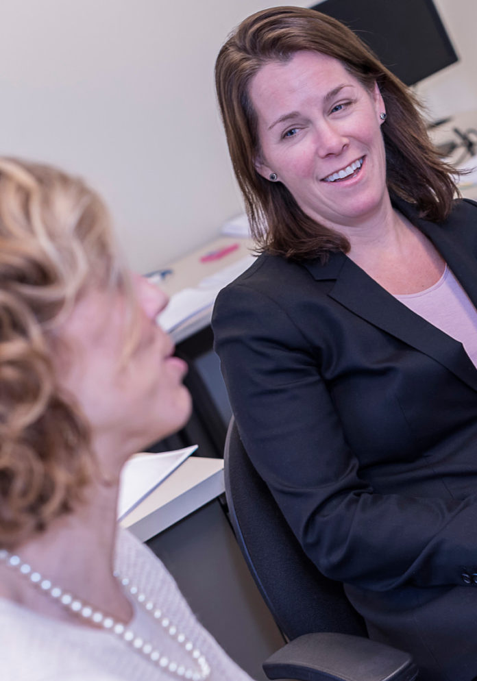ANYA RADER Wallack is leaving her position as state Medicaid director to take a position at Brown University. Here she is shown at HealthSource RI, talking with Contact Center Manager Meg Ivatts, on the left. / PBN FILE PHOTO/ MICHAEL SALERNO