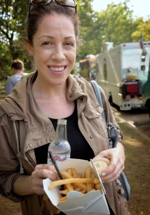 FINGER FOODIE: Katie Miller of Chicago was in town visiting friends and bought some food from the Friskie Fries food truck at Food Truck Friday at Roger Williams Park in Providence. / PBN PHOTO/MICHAEL SALERNO