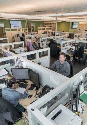 PROPELLED BY GROWTH: Neighborhood Health Plan of Rhode Island has new headquarters at 910 Douglas Pike in Smithfield. In cubicles facing each other are employees Maria Siera and Nate Byers. / PBN PHOTO/MICHAEL SALERNO