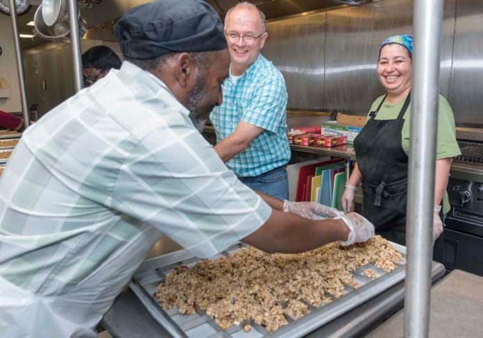 FOOD FOR THOUGHT: From left, Iman Diriye, a trainee at the Providence Granola Project, Keith Cooper, executive director of Beautiful Day, and Evon Mano, manager, are seen in Providence's Amos House kitchen, where Beautiful Day's granola is produced. / PBN PHOTO/MICHAEL SALERNO