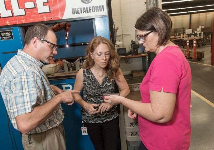 GROUP STUDY: Tracey MacNeal, center, chief strategy officer at ATW Companies, examines a pistol magazine with Elida Blazevic, assembly group leader, and Joel Allegrezza. / PBN PHOTO/ MICHAEL SALERNO