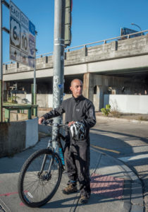 LOOKING FORWARD: Providence Mayor Jorge O. Elorza takes a break from his bike ride to work, which takes him underneath the Route 6-10 connector, shown in the background. He'd like to see a redesign of the roadway that connects divided neighborhoods. / PBN PHOTO/MICHAEL SALERNO