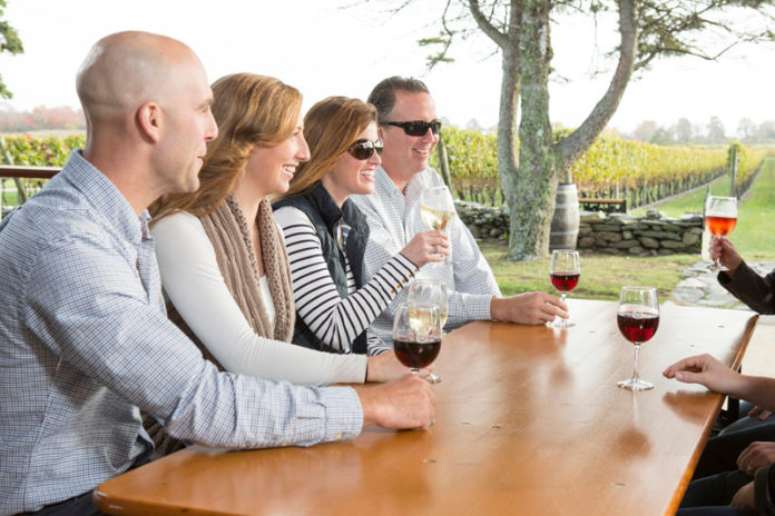 LOCAL  FLAVOR: Couples enjoy an outdoor wine tasting at Newport Vineyards, one of 14 vineyards and wineries that make up the Coastal Wine Trail in Southern New England. / COURTESY MARIANNE LEE PHOTOGRAPHY