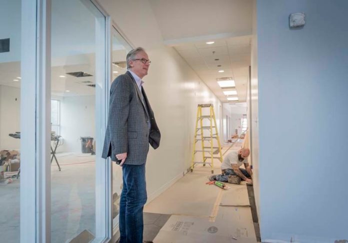 PREPPING: Scott A. Gibbs, president of The Economic Development Foundation of R.I., in the space it is outfitting for a national company. Bill Sincavage, of Domenic & Sons Floor Covering, works in the background. / PBN PHOTO/ MICHAEL SALERNO
