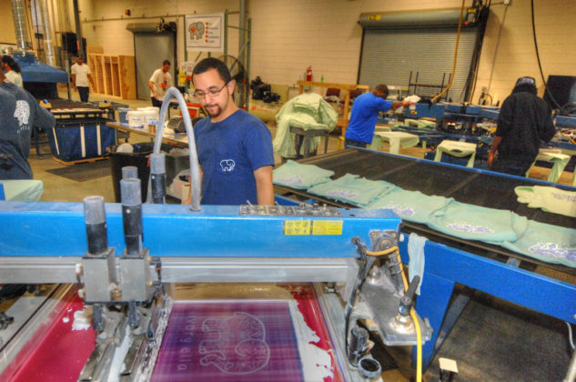 LIFESTYLE BRAND: Ivory Ella LLC screen printer Zachary Lespier works on the shop floor. The online retailer is known primarily for a variety of T-shirts bearing its distinctive elephant logo. / PBN PHOTO/BRIAN MCDONALD