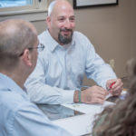 MAKING CONNECTIONS: Province Mortgage Associates CEO, President and Executive Director David Currie, center, makes a point of creating a work culture that values employees, who in turn value the firm's customers. Operations Manager Glenn Tourtellot is at left. / PBN PHOTO/MICHAEL SALERNO